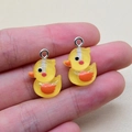 Close-up of small yellow resin duck charms with silver loops for DIY jewelry making - Duck