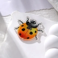 Detailed close-up of acrylic ladybug pendant with orange gradient and silver glitter finish - Yellow Ladybug