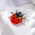 Close-up of ladybug acrylic charm with red glitter finish on white textured stone - Orange Ladybug