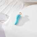 Enamel turquoise chili pepper charm pendant with gold metal loop on a white stone - Blue