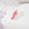 Pink enamel chili pepper pendant with gold metal loop on white textured stone background - Pink