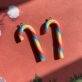 Close-up of colorful rainbow candy cane pendants with silver hooks on red background - Thick Rainbow Candy Cane