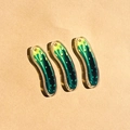 Macro shot of three realistic green acrylic pickled cucumber pendants for DIY jewelry - Strip Style / Cucumber