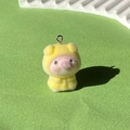 Makroaufnahme vom gelben beflockten Schweine-Anhänger mit weicher Textur und Metallring - Gelber Regenmantel Schwein