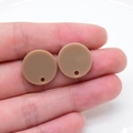 Vista macro di ciondoli rotondi in acrilico marrone chiaro tenuti in mano per gioielli fai-da-te - Caffè Rotondo