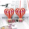 Close-up of heart hot air balloon wooden charms on book pages for DIY jewelry crafts - Striped Heart Hot Air Balloon (18)