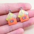 Detail of colorful resin house pendants with polka dot roofs and metal loops for DIY crafts - House