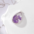 Macro shot of a teardrop resin pendant with real purple dried flowers and silver edging - Teardrop Purple Gypsophila