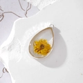 Macro shot of teardrop resin pendant with real yellow daisy flower and silver metal frame - Teardrop Yellow Flower