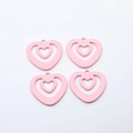 Detail view of four light pink hollow heart-shaped alloy charms for DIY jewelry making - Pink