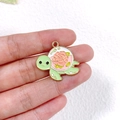Detailed macro view of a cute green turtle alloy charm with pink floral enamel patterns - Flower Turtle