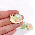 Close-up of a colorful enamel snail pendant with floral patterns for DIY jewelry making - Flower Snail