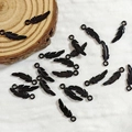 Macro detail of glossy black feather pendants for DIY jewelry making on wooden prop - Feather