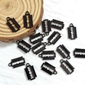 Detailed view of black alloy razor blade pendants on a natural wood block for DIY jewelry - Blade