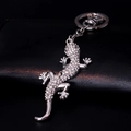 Elegant lizard keychain with sparkling rhinestones on black leather background - Silver