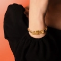 Grobe goldene Gliederkette mit zwei rechteckigen Metallanhängern an einer Frau - Armband / Herren Gold