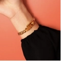 Massives goldenes Gliederkettenarmband mit Schlossverschluss auf orangefarbenem Hintergrund - Armband / Damen Gold