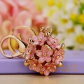 Pink enamel flower ball keychain with gold clasp on a gift box background - Pink