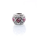 Macro-opname van zilveren bedel met roze kristallen en antieke geometrische patronen - Roze