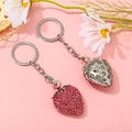 Macro view of sparkly pink strawberry rhinestone keychain with silver hollow metal backing - Strawberry