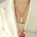 Double-layered gold necklace with triple rings and rectangular white shell pendant on model - White Shell Layered Necklace (P1380-1) / Gold