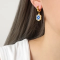 Vergulde oorringen met blauwe evil eye bloembedel gedragen door een model - Bloem Stijl (F282-D)