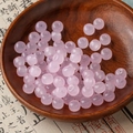 DIY translucent pink round glass beads for jewelry making displayed on a wooden plate - Pink