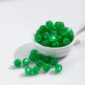 Translucent green agate resin beads for DIY jewelry making displayed in a porcelain spoon - 10mm Deep Green Cat Eye