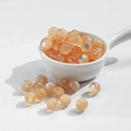 Polished 10mm amber resin beads in a white ceramic spoon for DIY jewelry making - 10mm Orange Cat Eye