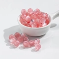 Pink translucent 10mm cat-eye effect resin beads in a white ceramic bowl for DIY jewelry - 10mm Pink Cat Eye