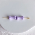 Détail de deux perles en forme d'os violet clair sur une tige dorée pour bijoux DIY - Lavande
