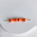 Gros plan de perles orange en forme d'os sur tiges dorées pour la création de bijoux DIY - Orange vif