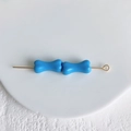 Gros plan de perles en forme d'os bleues sur tige dorée pour bijoux DIY - Bleu brillant