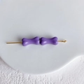 Gros plan détaillé de perles violettes en forme d'os sur épingle dorée pour bijoux DIY - Violet