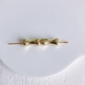 Vue macro de deux perles dorées en métal en forme d'os sur un plateau en céramique - Or