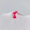 Close-up of a bright pink bone-shaped pendant accessory for DIY crafts and jewelry - Rose Pink Bone Style