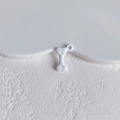 Close-up of white bone-shaped matte alloy charm with hanging ring for DIY jewelry making - White Bone Style