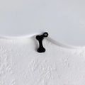 Macro detail of bone shaped black enamel alloy pendant with integrated hanging loop - Black Bone Style