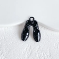 Macro shot of black enamel twin shoe charms with metallic hooks for DIY jewelry making - Black Ballet Shoes Style