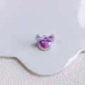 Detail of aurora purple acrylic bow charm on a white decorative ceramic plate - Iridescent Purple