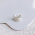Macro shot of white acrylic bow bead with iridescent pearl finish for DIY jewelry craft - Pearlescent White