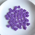 Close-up of purple hollow heart beads with butterfly patterns for DIY jewelry making - Purple