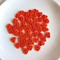 Close-up of bright orange hollow heart beads with floral cutouts for DIY jewelry making - Bright Orange