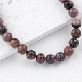 Polished natural pink stone bead bracelet with black patterns on a white textured base - 1 Piece / Rhodonite 10mm