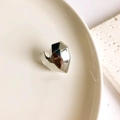 Close-up of faceted silver heart-shaped earring on ceramic plate with modern geometry - Silver Heart