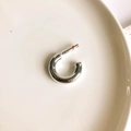 Macro view of a silver C-shaped hoop earring on a cream ceramic plate with clasp detail - Silver C-Shape (Small)