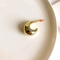 Detailed view of polished gold crescent stud earrings with unique red dot detail on white ceramic - Gold Fat Crescent