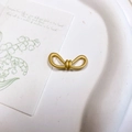Vue macro détaillée d'un accessoire en métal doré mat en forme de nœud sur une carte - Nœud Enveloppé Or Sable