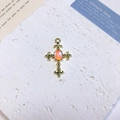Detailed view of vintage gold cross pendant with oval opal stone and lily ends - Fleur-de-lis Oval Cross / Orange + Gold Pattern