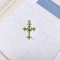 Detailed view of vintage gold cross pendant with opal stone on a stone surface - Fleur-de-lis Oval Cross / Blue + Gold Pattern
